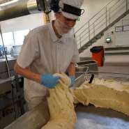 (FOTO: Inken Paletta, Finntastic) Ein Mitarbeiter schneidet die Teigmasse in passende Stücke. 